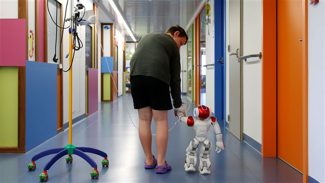 Belgian Ian Frejean, 11, walks with *Zora* the robot, a humanoid robot designed to entertain patients and to support care providers, at AZ Damiaan hospital in Ostend, Belgium June 16, 2016.