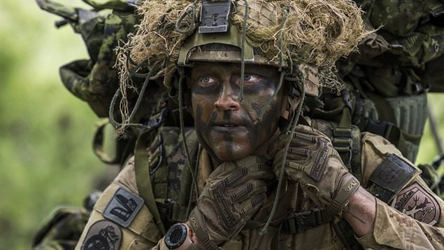 Master Corporal Audie Ste. Croix from 1st Battalion, The Royal Canadian Regiment, dressed as enemy force for the exercise, adjusts his helmet during Exercise MAPLE RESOLVE in Wainwright, Alberta on 1 June, 2016.