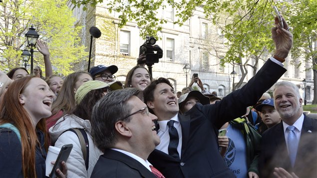 The Prime Minister Justin Trudeau stops for selfies as Premier of Quebec Philippe Couillard and Mayor Coderreas look as they walk to the Notre-Dame Basilica to attend a mass marking the 375th anniversary of the founding of Montreal on Wednesday May 17, 2017.