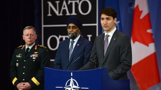 Prime Minister Justin Trudeau stands with Defence Minister Harjit Sajjan, centre, and Chief of Defence Staff Gen. Jonathan Vance as he holds a press conference at NATO headquarters in Brussels on Thursday.