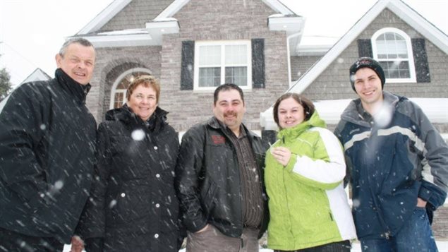 New Brunswick resident Sarah Cleveland and her family pose outside her Hospital Home Lottery prize in December 2011. Winners of homes say they have been selling them because they can’t afford to maintain them