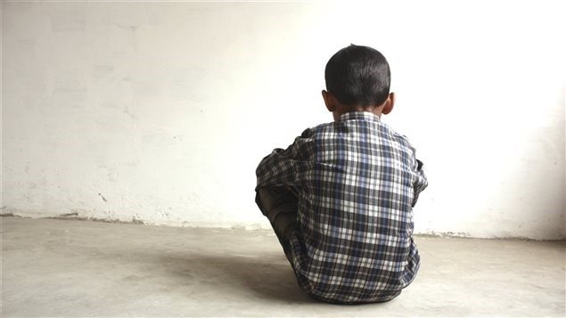 Un enfant assis face à un mur