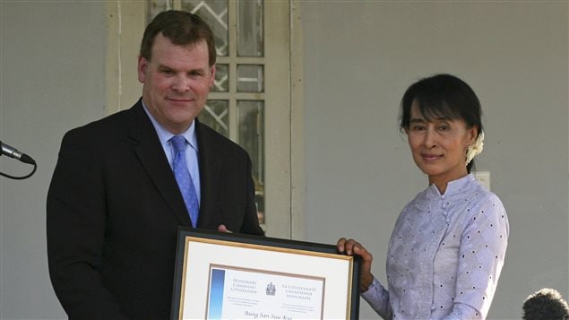 Myanmar’s pro-democracy leader Aung San Suu Kyi (R) accepts the award of Honorary Canadian citizenship from Canada’s Foreign Minister John Baird, after their meeting at Suu Kyi’s home in Yangon March 8, 2012.