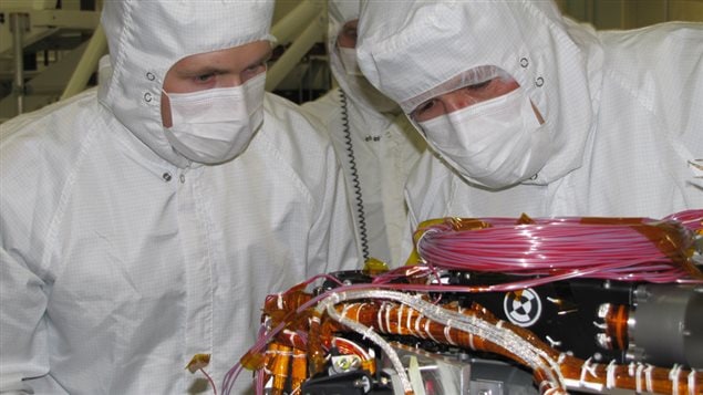 Nicholas Boyd (left) and Ralf Gellert (right), the Principal Investigator for APXS, prepare the instrument for the installation of the sensor head during testing at NASA’s Jet Propulsion Laboratory (JPL) in California.
