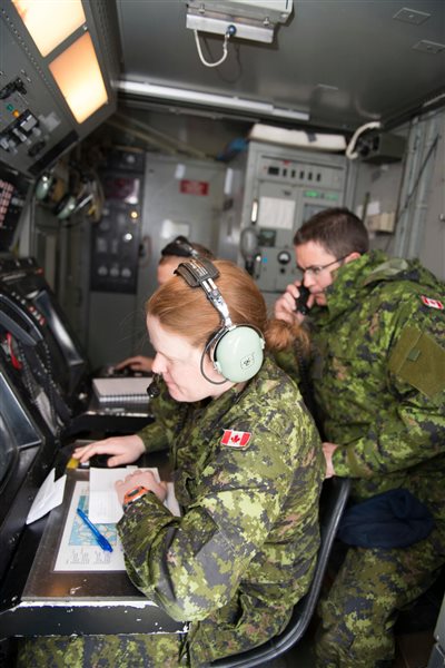 Captain Meghan McCready (left), Aerospace Controller with 12 Radar Squadron, watches the control radar screen while Master Corporal Patrick Flynn (right), Air Control Operator with 12 Radar Squadron, relays the information during Exercise AMALGAM DART 15-2 in Resolute Bay, Nunavut on May 31, 2015.