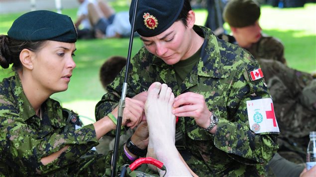 Master Corporal Natasha Lauzon of 1 Canadian Field Hospital in Petawawa, Ontario, and Sergeant Valerie Charbonneau, a medic with 55 Field Ambulance in Quebec City, Quebec, tend to the foot of a Canadian Armed Forces Nijmegen marching team member, during the Nijmegen Marches in the Netherlands, on July 23, 2015.
