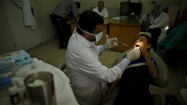 طبيب أسنان يقوم بمعاينة فتى فلسطيني في مركز صحي تابع لوكالة الأونروا في قطاع غزة في أيلول (سبتمبر) 2015.
