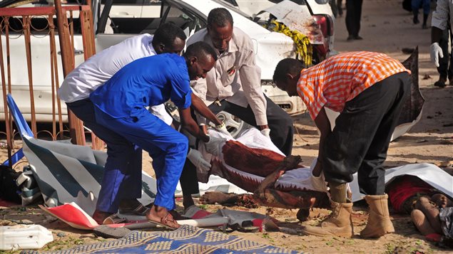 Hombres transportan los cuerpos de la víctimas del atentado al restaurante Pizza House de Mogadiscio este jueves 15 de junio 2017.