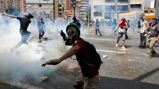 A demonstrator throws a tear gas canister back to policemen during an opposition rally in Caracas, Venezuela, April 6, 2017. 