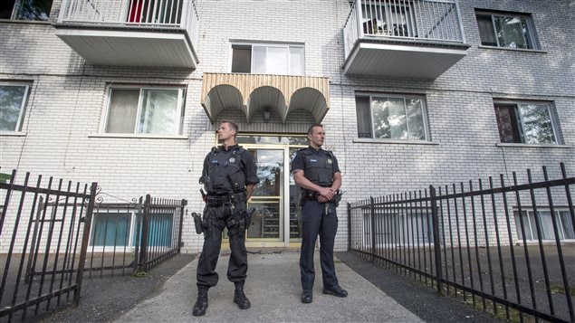 Police stand guard in front of an apartment building in Montreal, Wednesday, June 21, 2017. U.S. law enforcement authorities say a man allegedly involved in the stabbing of a police officer at a Michigan airport is a Canadian resident. 