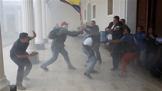 A government supporter holds a National flag while clashing with people outside Venezuela’s opposition-controlled National Assembly, in Caracas. 