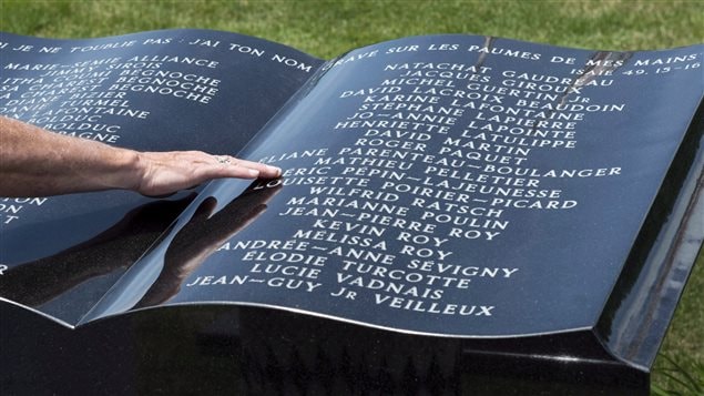 A man touches a stone monument in front of Ste-Agnes church following a memorial service for the 47 victims of an oil-filled train derailment. Photo taken on Sunday, July 6, 2014 in Lac-Megantic, Que.