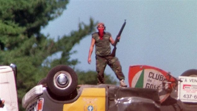 July 11, 1990: A Mohawk man stands on an overturned police vehicle blocking a highway through Kanesatake. 