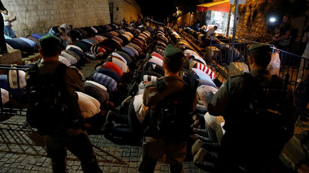 عناصر من شرطة الحدود الإسرائيلية يراقبون المصلين الفلسطينيين وهم يؤدون صلاة العشاء يوم الثلاثاء عند بوابة الأسباط، إحدى بوابات المسجد الأقصى