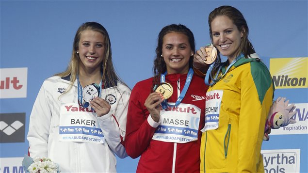 Canada’s gold medal winner Kylie Jacqueline Masse is flanked by United States’ silver medal winner Kathleen Baker, left, and Australia’s bronze medal winner Emily Seebohm, right, during the ceremony for the women’s 100-meter backstroke final during the swimming competitions of the World Aquatics Championships in Budapest, Hungary, Tuesday, July 25, 2017.