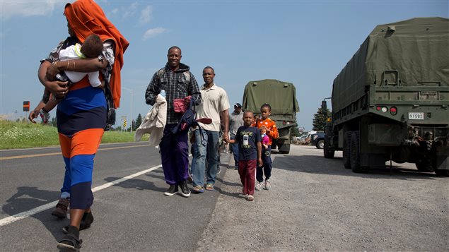 Un grupo de solicitantes de asilo caminan hacia su carpa en el puesto fronterizo de Lacolle, Quebec.