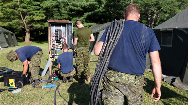 Soldados de la Fuerzas Armadas canadienses instalan el servicio eléctrico en las carpas de los refugiados.