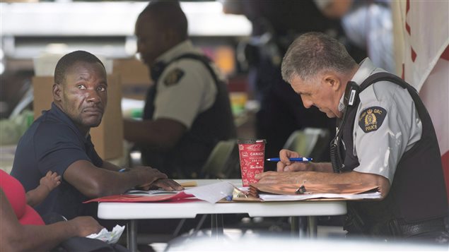 An asylum seeker is processed by RCMP officers after crossing the border into Canada from Champlain, N.Y., in Hemmingford, Que., Friday, August 4, 2017.