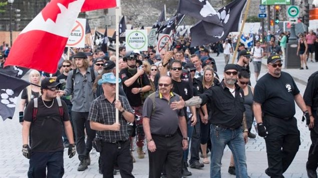 Hours after the planned start, members of La Meute march sliently to the Quebec legislature to protest the wave of migrants crossing illegally into Canada from the U.S. before claiming asylum.