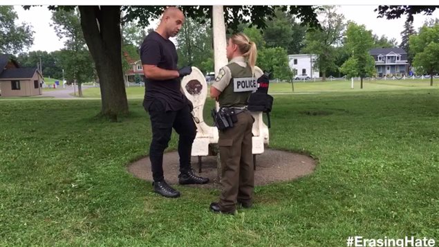 Corey Fleiecher of *Erasing Hate* speaking with a police officer abour his effort to block out the swastika symbol
