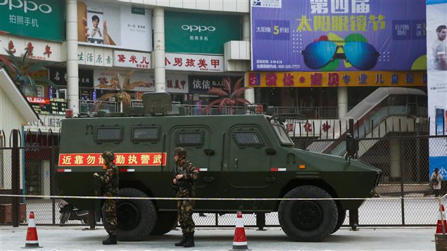 Security personel stand in front of an armoured vehicle in Kashgar, Xinjiang Uighur Autonomous Region, China, March 24, 2017.