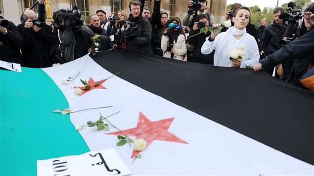 الناشطة السلمية السورية فدوى سليمان مرتدية اللون الأبيض تنثر وروداً بيضاء على علم الجمهورية السورية الأولى الذي أعاد اعتماده معارضو الرئيس السوري بشار الأسد، في تظاهرة ضد نظامه في ساحة تروكاديرو في باريس في 17 نيسان (أبريل) 2012 الذي صادف الذكرى السنوية الـ66 لتاريخ جلاء آخر جندي فرنسي عن الأراضي السورية