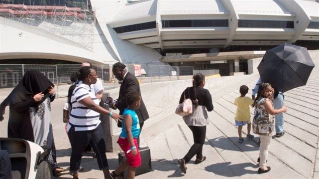 A group of asylum seekers leave Olympic Stadium to go for a walk in Montreal on Wednesday. The stadium is being used as temporary housing to deal with the influx of asylum seekers arriving from the United States.