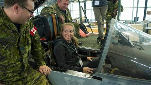 A participant of the Women in Force programme sits in a CF-18 Hornet and chats with a military members about the jet at the 400 Squadron in Canadian Forces Base (CFB) Borden, Ontario on August 17, 2017. In the Canadian Forces, in addition to dozens of other options, from, doctor, lawyer, vehicle mechanic etc, women can choose tobecome front line combattnats including fighter jet pilots.