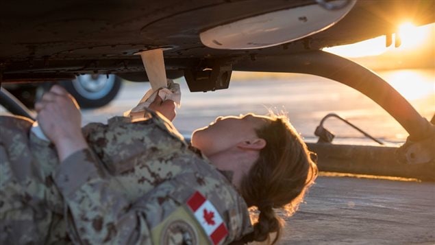 A Canadian Armed Forces Avionics Systems Technician inspects and cleans a CH-146 Griffon helicopter at Camp Érable, Iraq during Operation IMPACT on April 25, 2017.