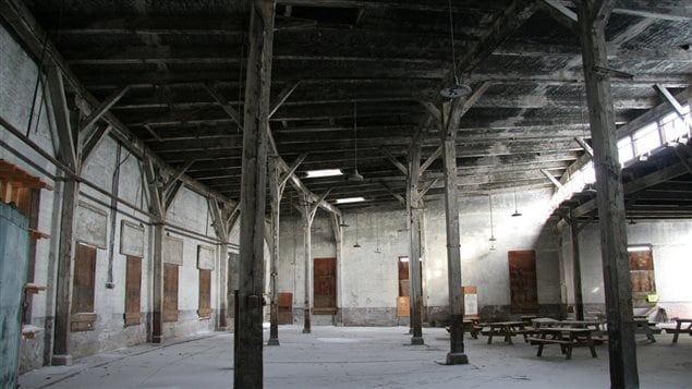 Interior of the Canadian Northern Railway Roundhouse, December 2013. The fan-shape of the building is evident in the curvature of the rear wall (to the left), the clerestory windows (at the right) and the arrangement of the ceiling supports and beams.