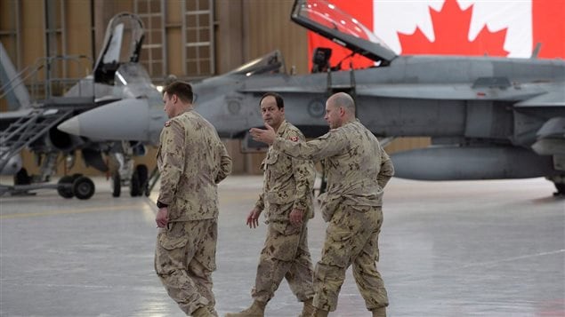 Chief of the Defence Staff Tom Lawson (centre) walks past two F-18 fighter jets as he talks with fellow members of the Canadian Forces at Camp Patrice Vincent in Kuwait on Sunday, May 3, 2015. Three retired air force generals say buying used fighter jets from Australia is a much better plan for Canada than purchasing new Super Hornets from Boeing. 