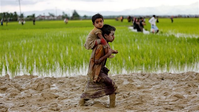 A Rohingya boy carries a child while walking in the mud after crossing the Bangladesh-Myanmar border in Teknaf, Bangladesh, September 1, 2017. 