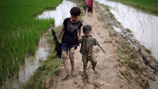 Rohingya refugee children walk on a muddy path after crossing the Bangladesh-Myanmar border, in Teknaf, Bangladesh.
