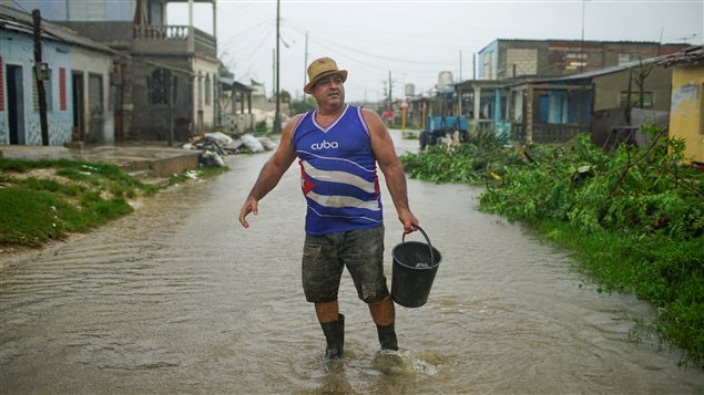 A man talks to his neighbour (not pictured) as he collects water to clean his front door after the passage of Hurricane Irma in Caibarien, Cuba, September 9, 2017.