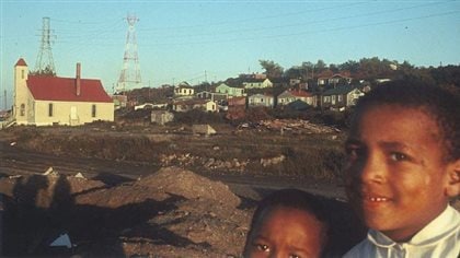 Two children pose in 2016 in front of what is left of Africville, a once-vibrant community in Halifax, Nova Scotia.