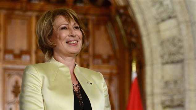 Mme Nemer sourit devant un drapeau canadien lors de la conférence de presse annonçant sa nomination