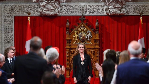Laurier Payette Flynn, left, looks on as his mother, Canada's 29th Governor General Julie Payette, is applauded following her speech in the Senate on Parliament Hill in Ottawa on Monday.