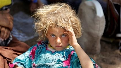 A Yazidi girl fleeing the violence in the Iraqi town of Sinjar rests at an Iraqi-Syrian border crossing in in July, 2016.