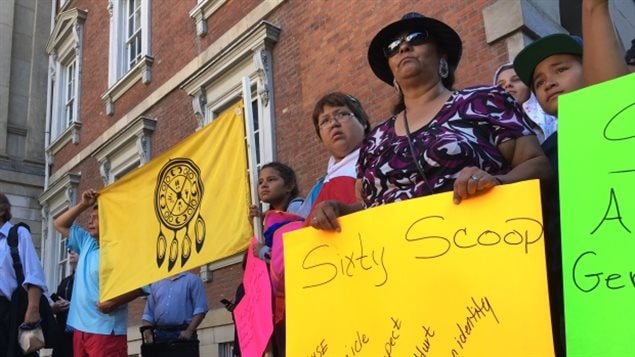 Supporters of the Sixties Scoop hold signs and flags outside a Toronto courthouse during a rally in 2016. 