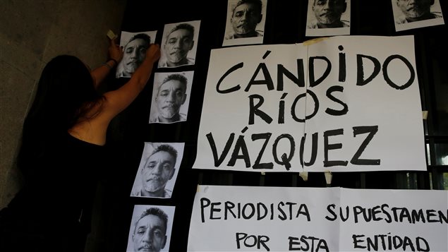 Periodista pega fotos del reportero Cándido Ríos, asesinado en Veracruz, México. 