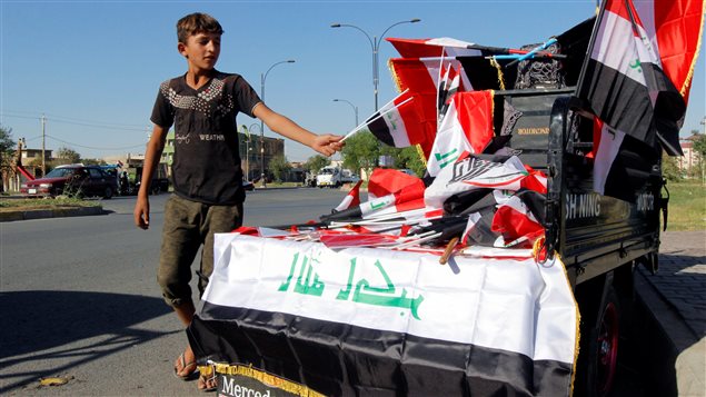 فتى يبيع أعلاماً عراقية في أحد شوارع مدينة كركوك أمس.