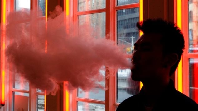 A man exhales vapour from an e-cigarette. The government should continue to work to limit sales to youth, the Canadian Medical Association says. 