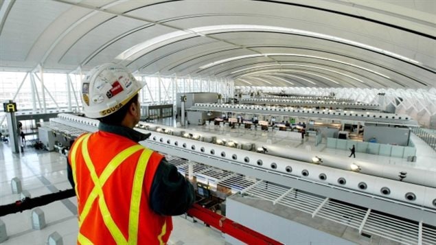 Aecon Construction scissor lift operator, Abel Sousa, looks at Toronto Pearson International Airport’s new Terminal 1 check-in area from above the scissor lift on Dec. 2, 2003.