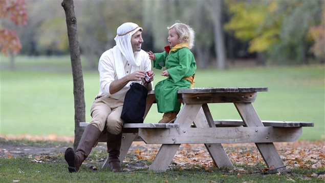 Prime Minister Justin Trudeau, dressed as the Pilot from The Little Prince, and his son Hadrien, dressed as the Little Prince, have a treat after trick-or-treating at Rideau Hall, on Halloween, Monday, Oct. 31, 2016 in Ottawa. 