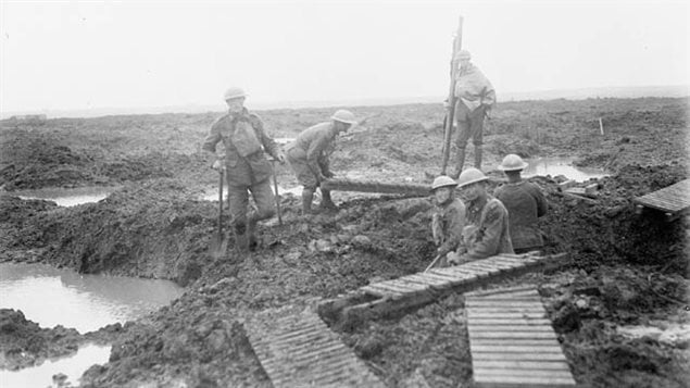 Canadian soldiers laying tench mats or *duck boards* over the mud to give some degree of footing to soldiers.