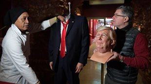 Le sculpteur Eric Saint Chaffray s’apprête à poser une tête de cire de Donald Trump sur le buste. (CHRISTOPHE ARCHAMBAULT / AFP)