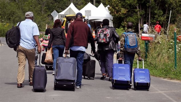 August 2017: A Haitian family haul their luggage at a known illegal crossing into Quebec earlier this year from New York state in order to claim asylum. 
