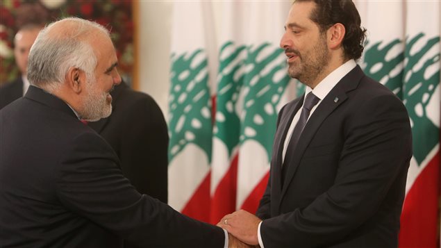مصافحة بين رئيس الحكومة اللبنانية سعد الحريري (إلى اليمين) الذي علّق استقالته من منصبه وسفير إيران لدى لبنان محمد فتحلي اليوم في القصر الرئاسي في بعبدا إلى الشرق من بيروت