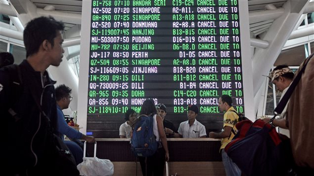 Passengers ask staff about their flights near the flight screen after Ngurah Rai airport closed their operation due to eruption of Mount Agung in Bali resort island, November 27, 2017.