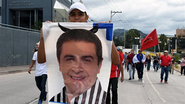 Un partidario del candidato opositor Salvador Nasralla sostiene un afiche del presidente Juan Orlando Hernández durante una marcha el 3 de diciembre de 2017 en Tegucigalpa, a pesar del estado de emergencia y el toque de queda de 10 días impuesto por el gobierno para detener las violentas manifestaciones provocadas por reclamos de fraude electoral presidencial. 